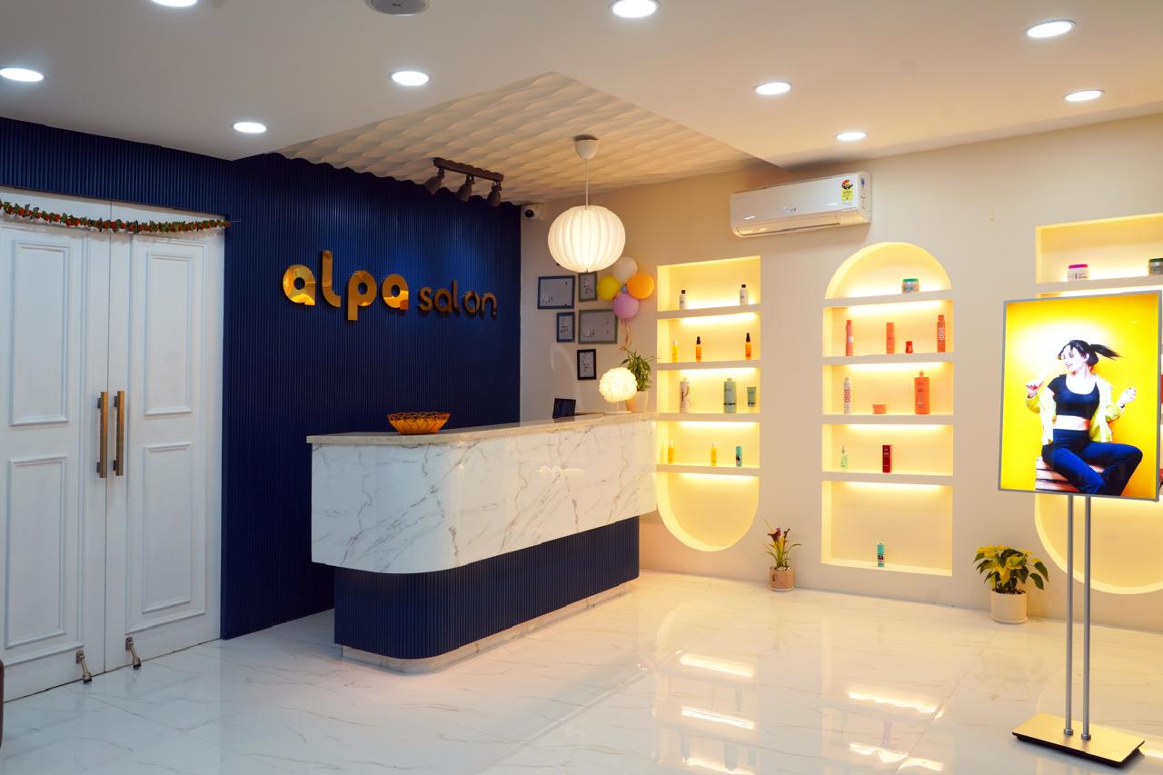 Alpa Salon reception — navy logo wall, white marble desk and backlit golden arches