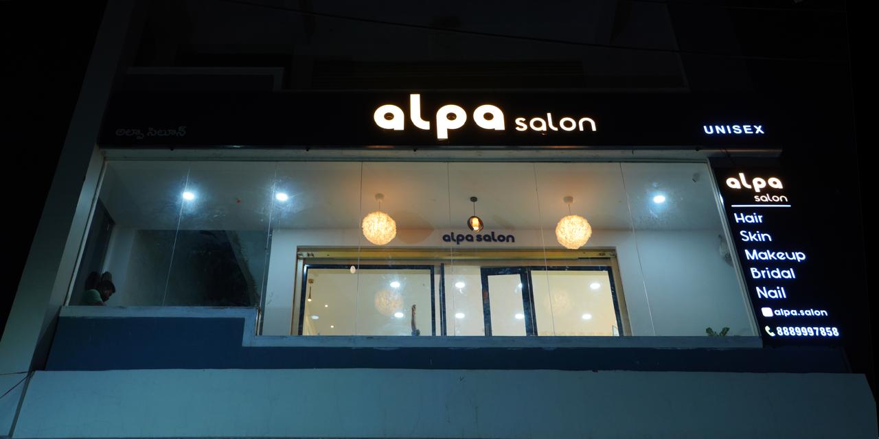 Alpa Salon building facade at night with the glowing gold signboard