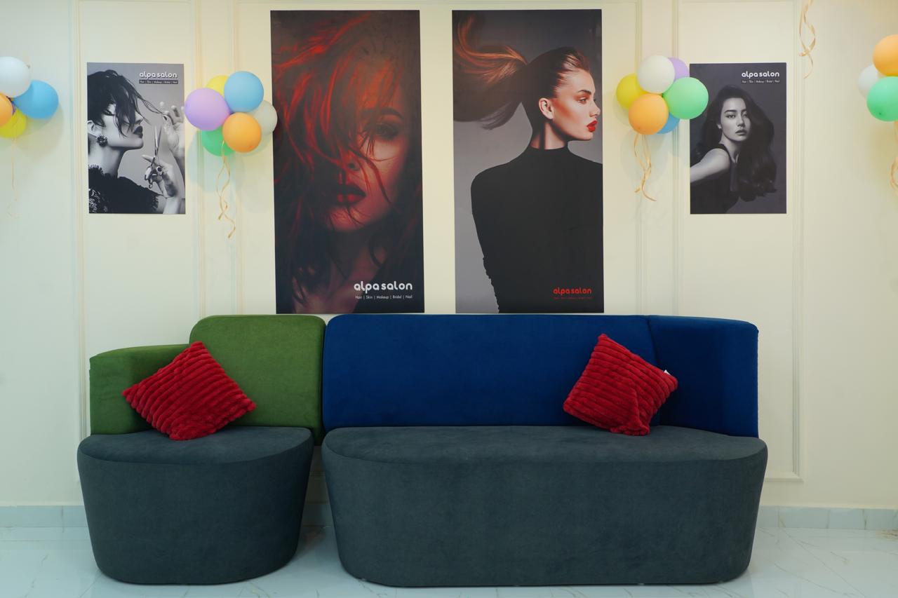 Waiting lounge with emerald and navy sofas, red cushions and fashion posters