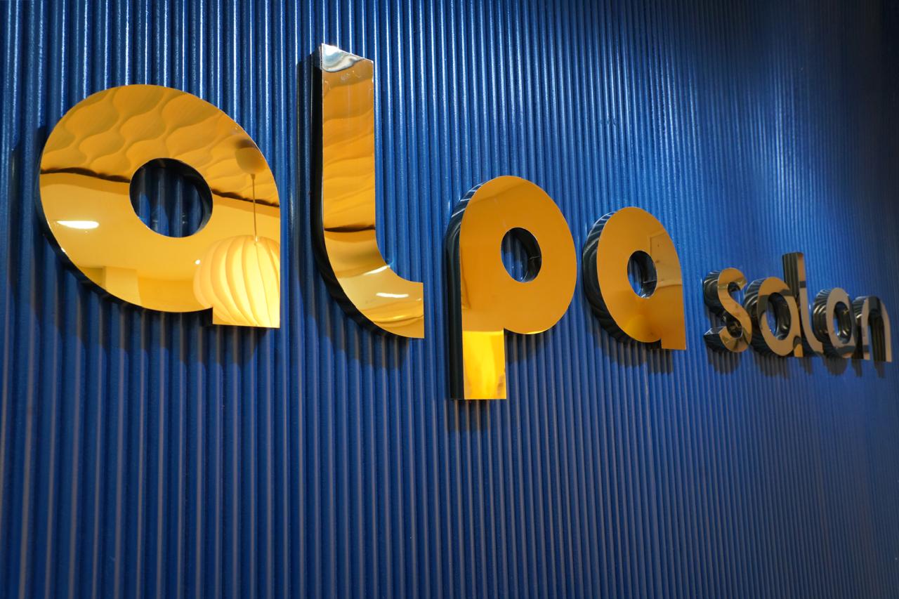 Close-up of the gold 'alpa' letters on the cobalt ribbed wall